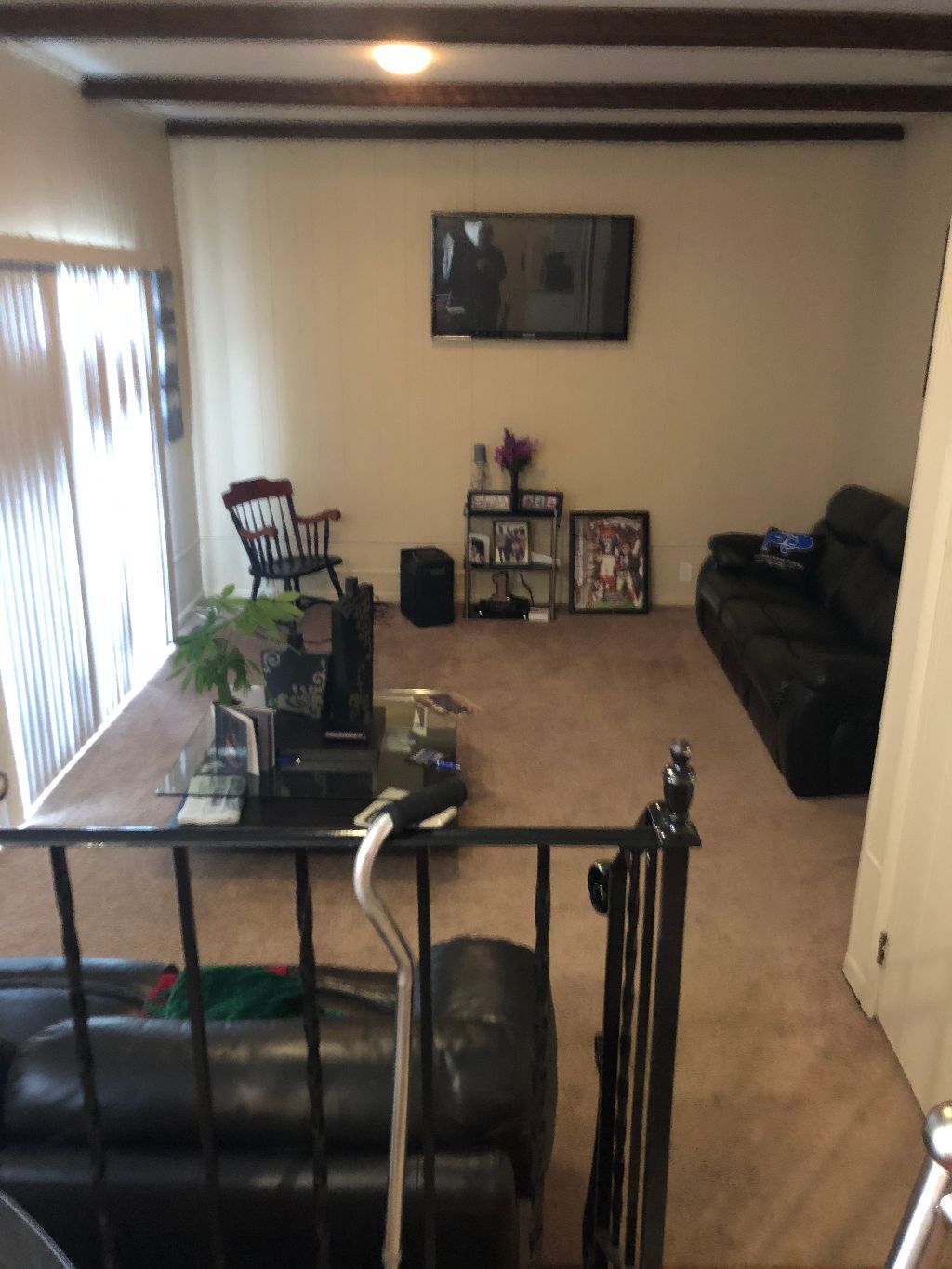 A living room with a black couch and a tv on the wall