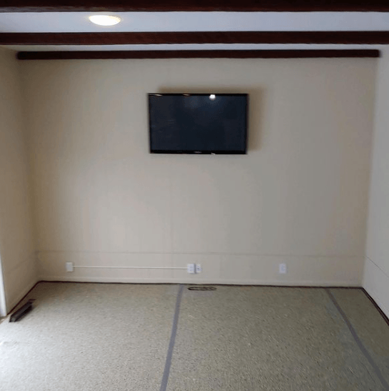 An empty room with a flat screen tv mounted on the wall.
