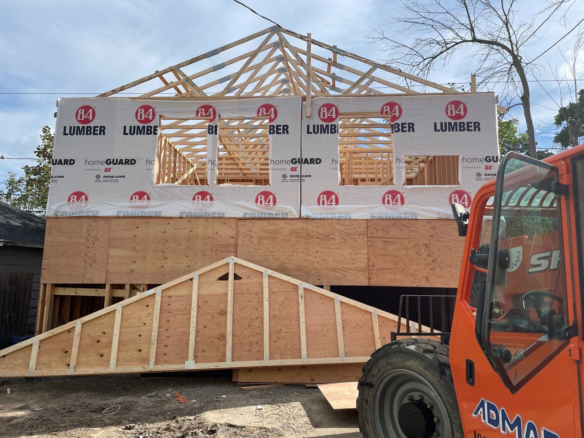 A forklift is parked in front of a house under construction.