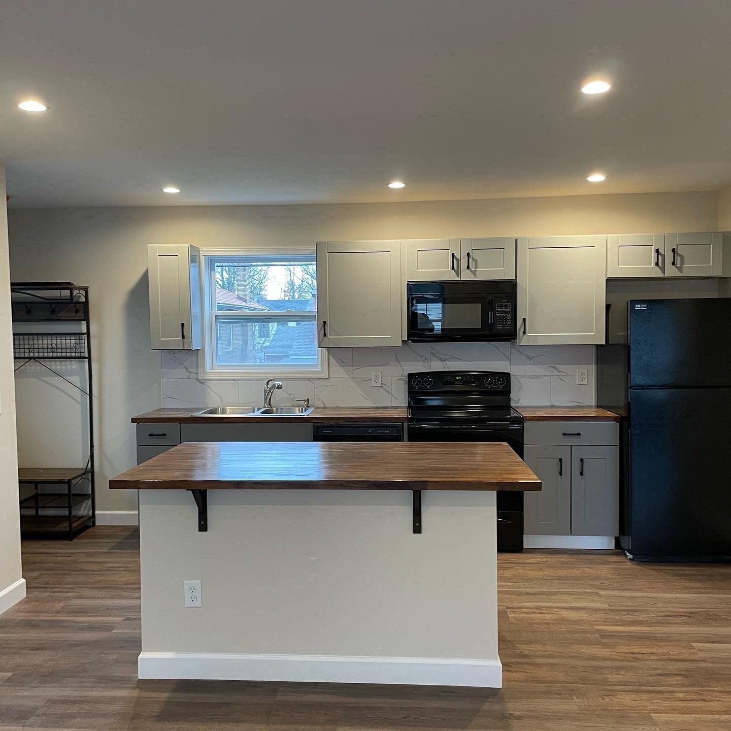 A kitchen with a large island , stove , refrigerator , microwave and sink.