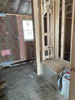 A bathroom under construction with a bathtub and a window.