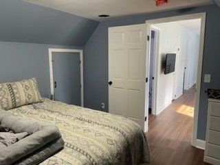 A bedroom with a bed , dresser , and television.