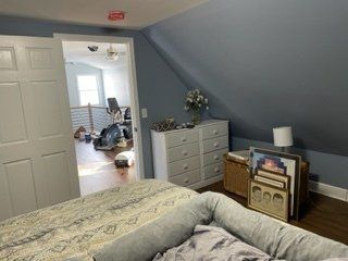 A bedroom with a bed , dresser , and a dog bed.