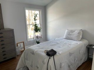 A bedroom with a single bed , dresser , and window.