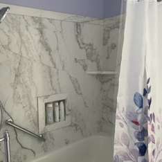 A bathroom with a shower , tub , shower head and shower curtain.
