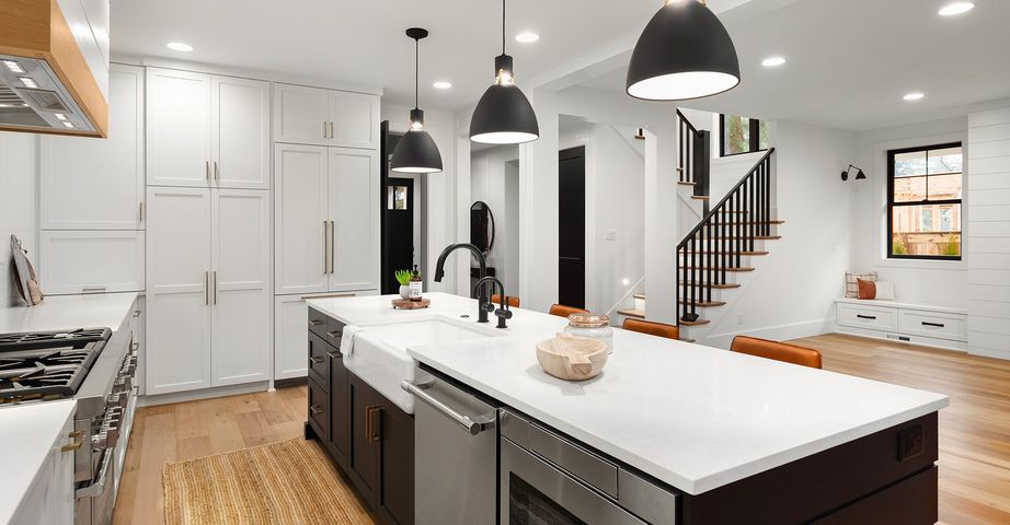 A kitchen with white cabinets , stainless steel appliances , and a large island.