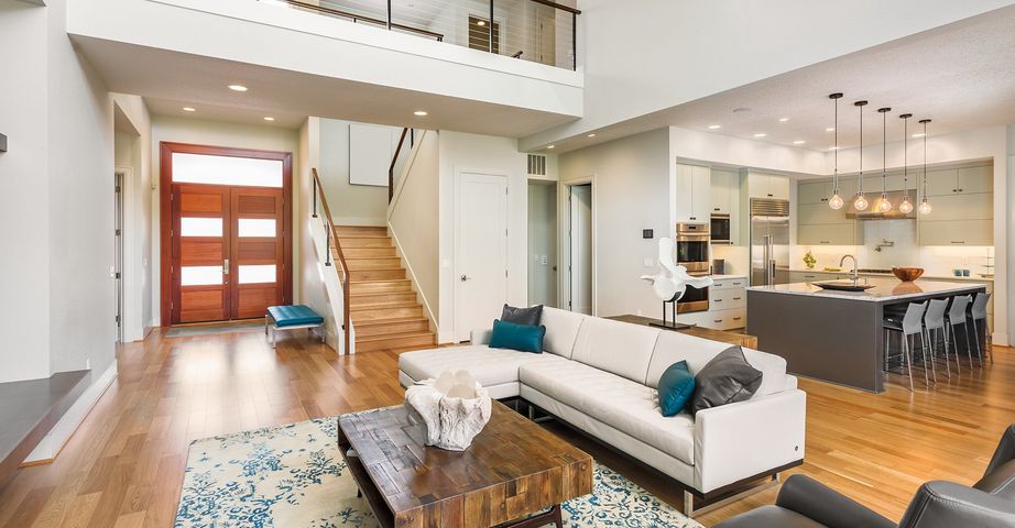 A living room with a white couch , coffee table , chairs and stairs.