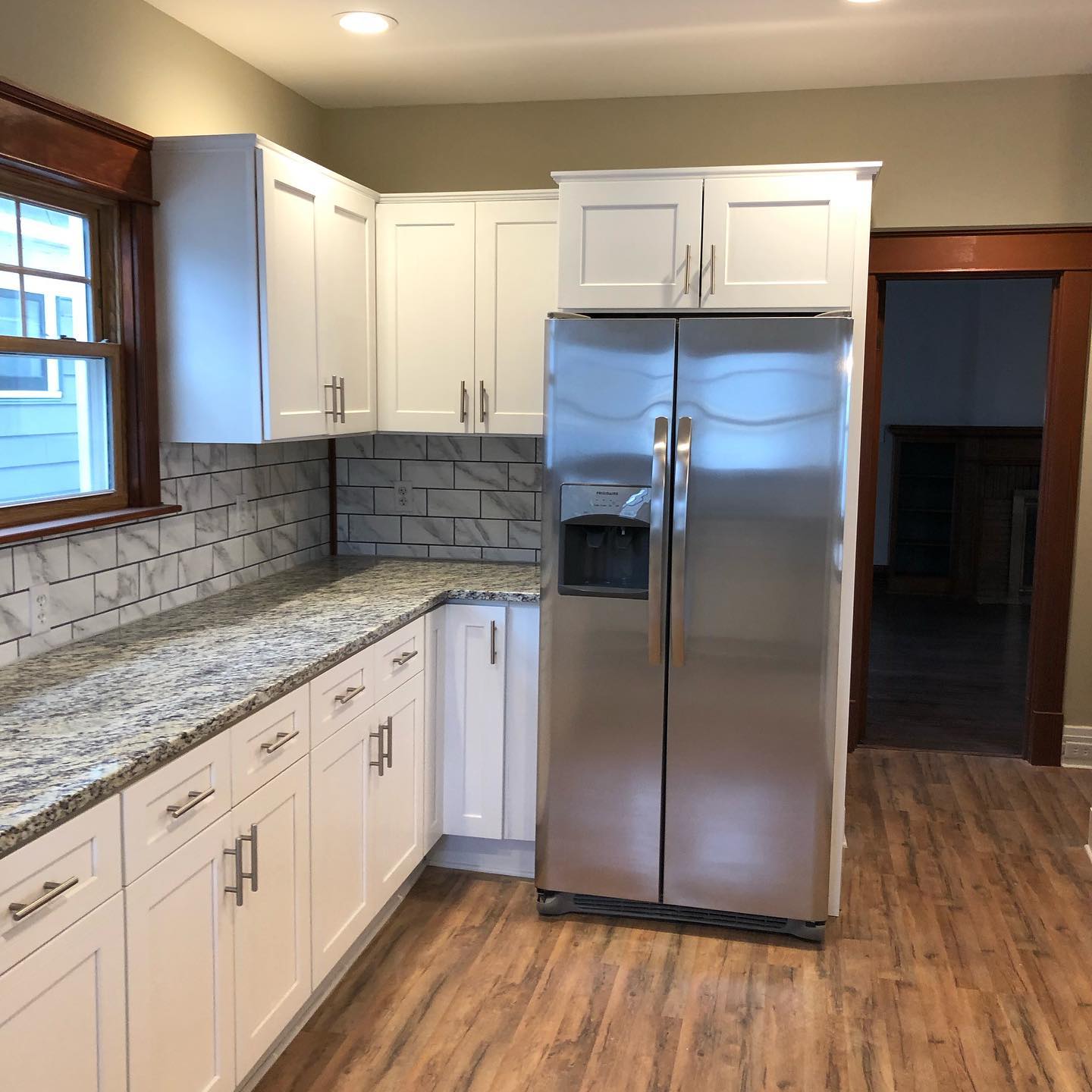 A kitchen with white cabinets and a stainless steel refrigerator