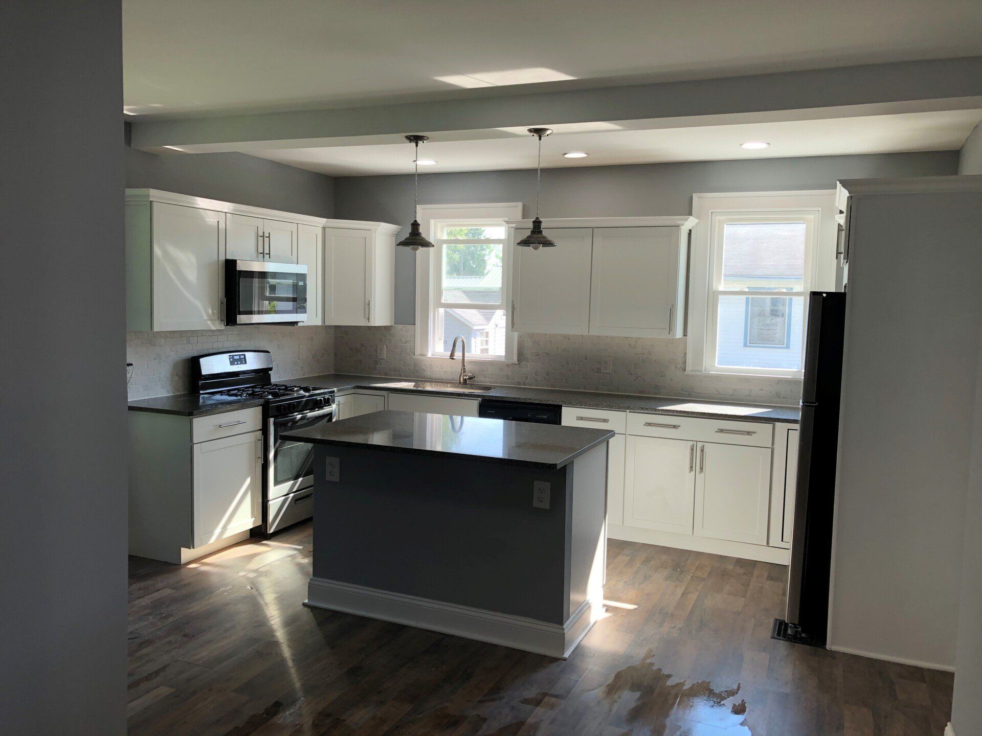 A kitchen with white cabinets , black appliances , and a large island.