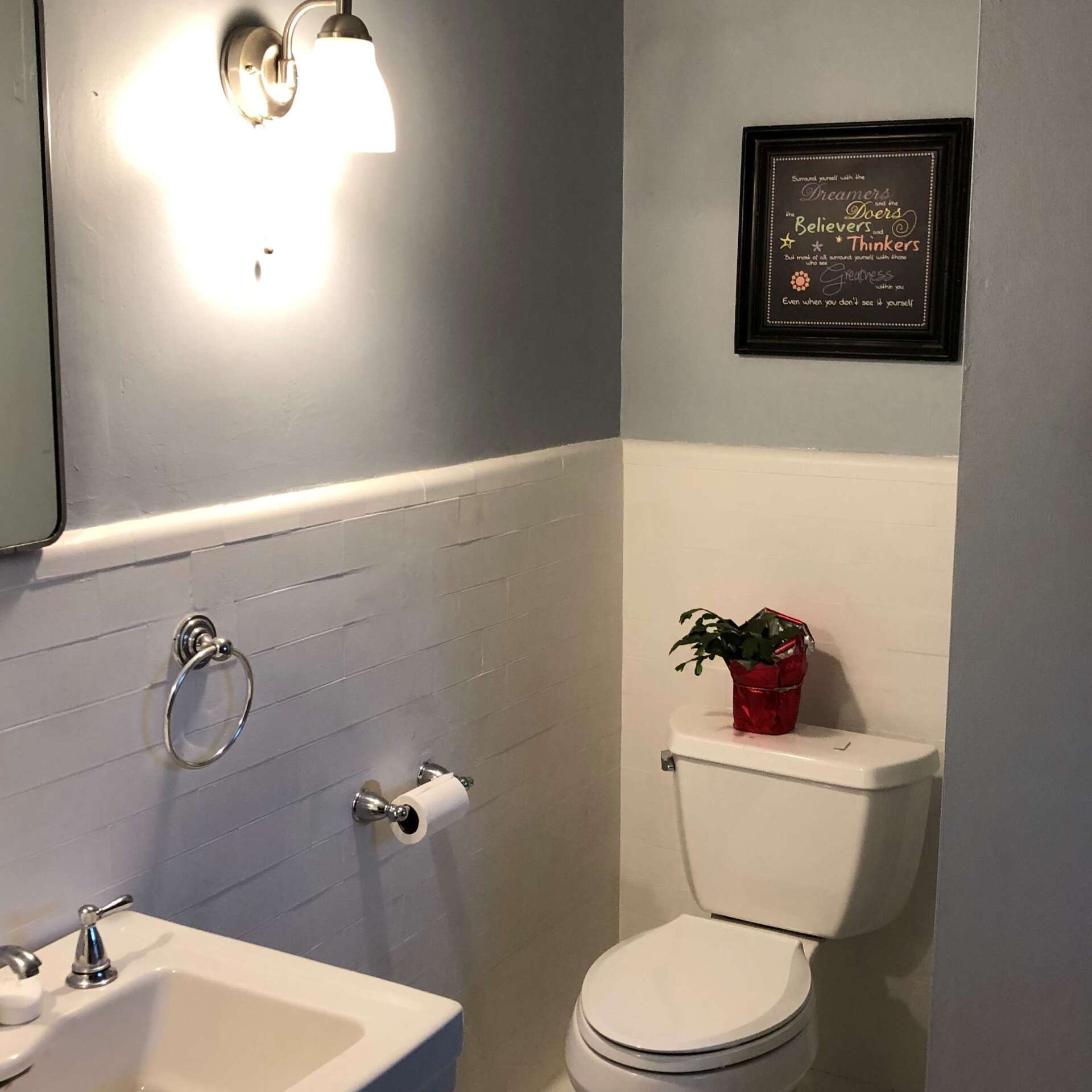 A bathroom with a toilet a sink and a picture on the wall