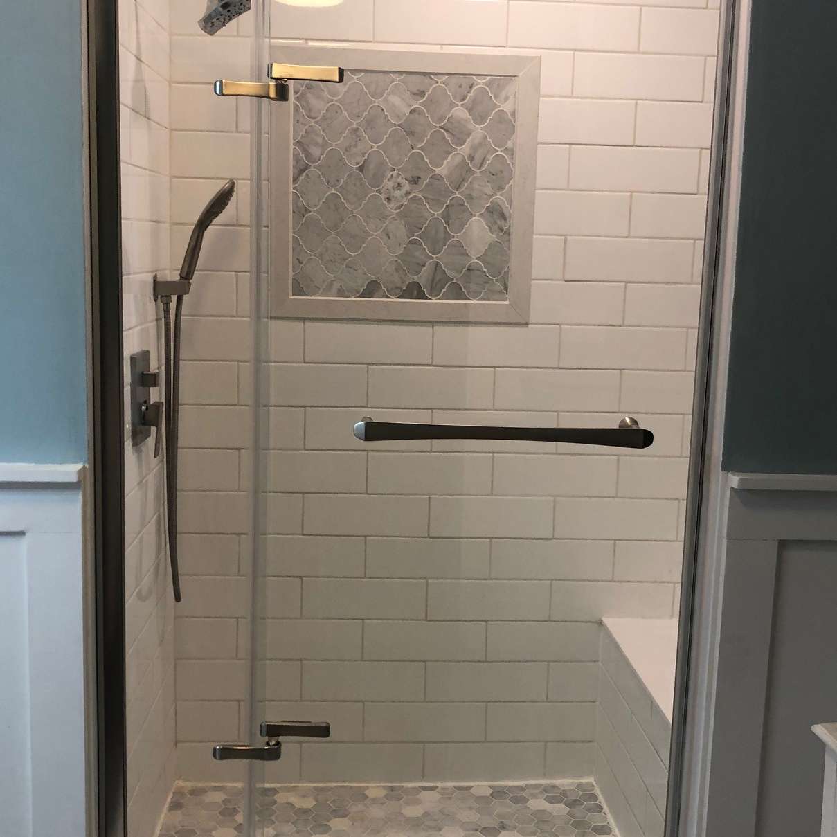A bathroom with a walk in shower with a glass door.
