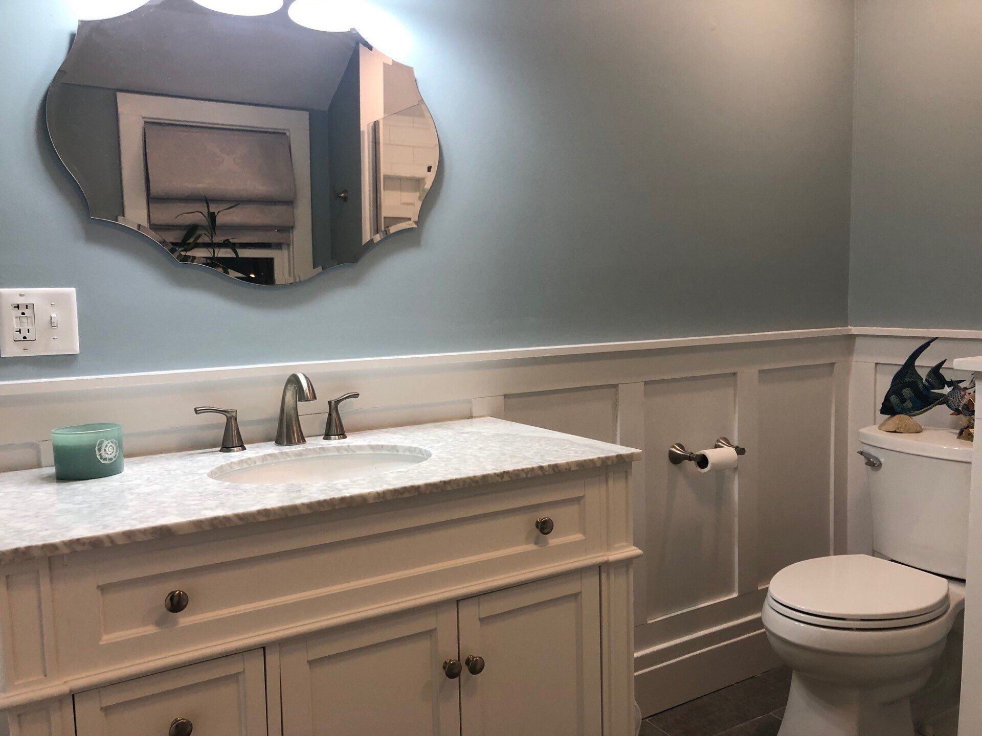 A bathroom with a sink , toilet and mirror.