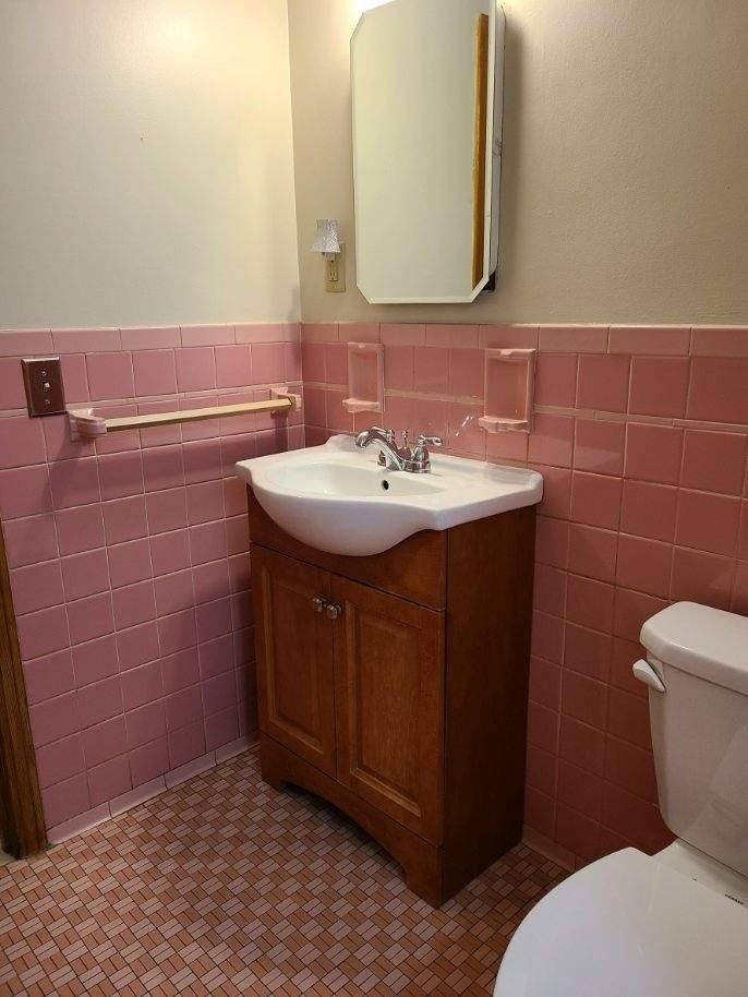 A bathroom with pink tiles and a sink and toilet