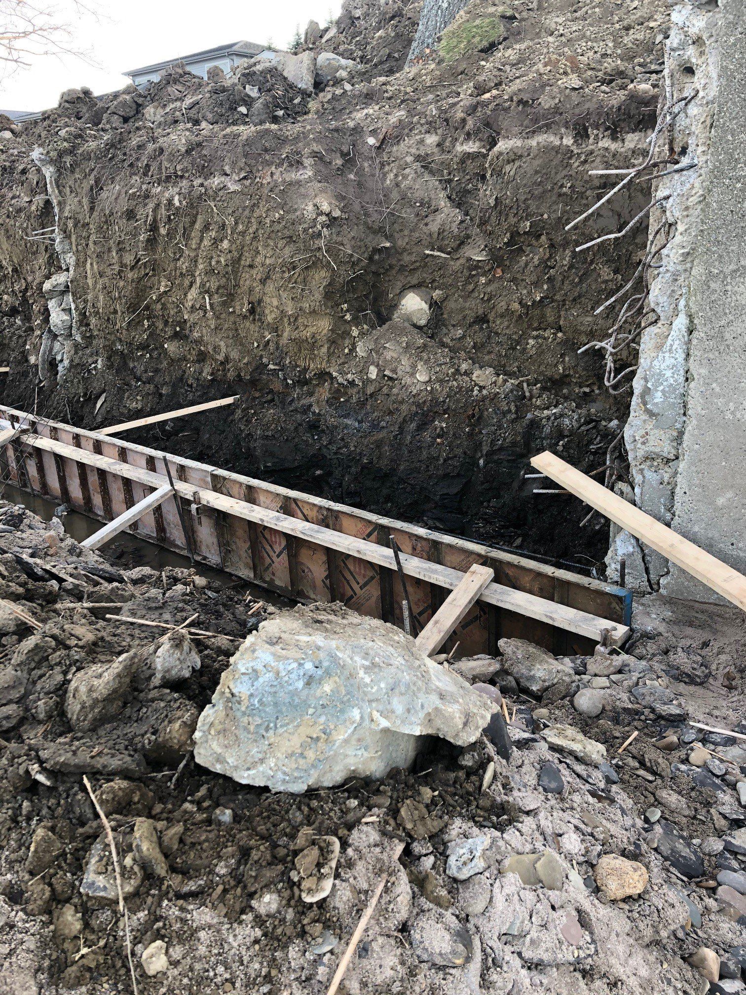 A large rock is laying on top of a pile of dirt.
