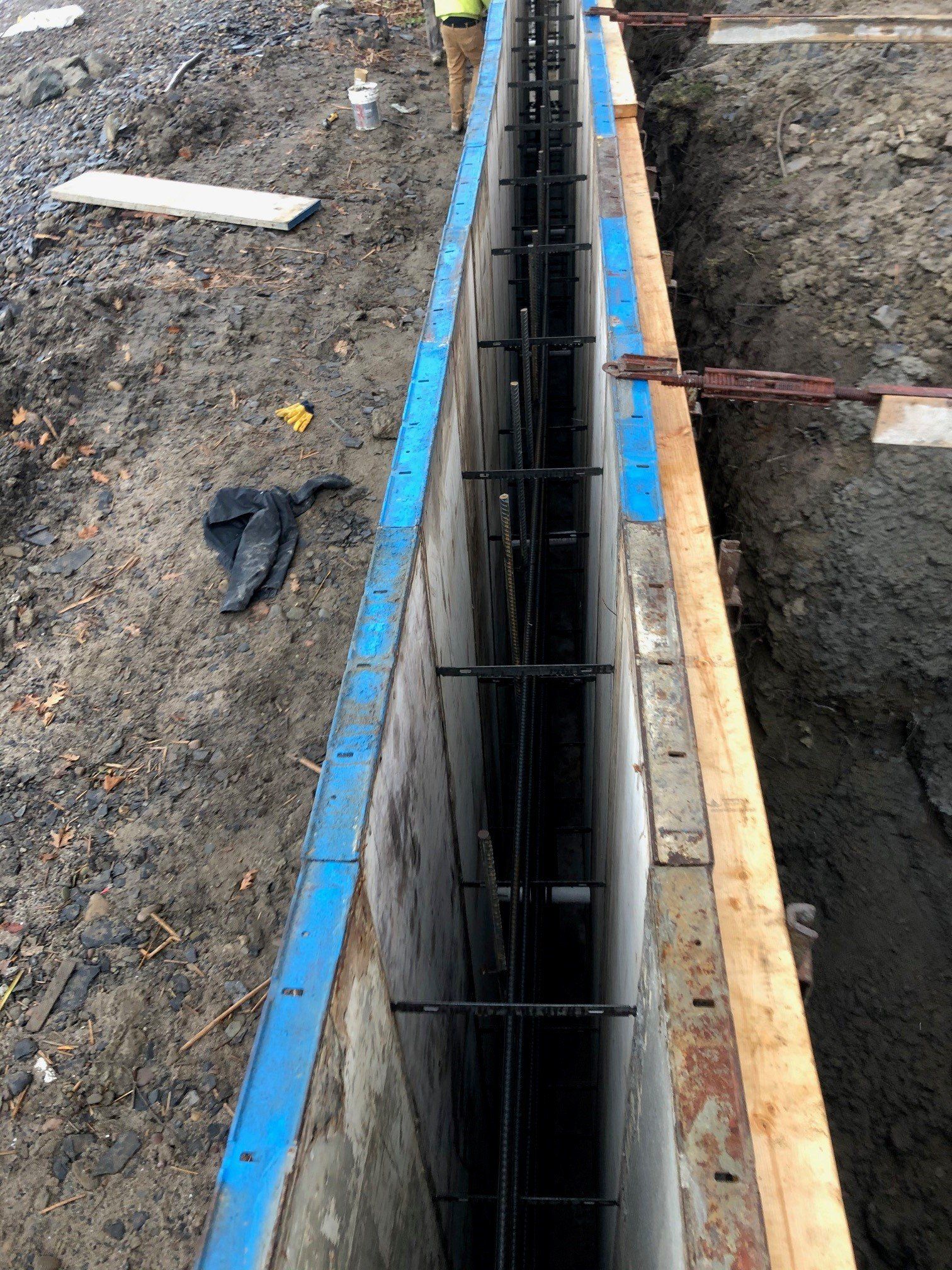 A concrete wall is being built in a hole in the ground.