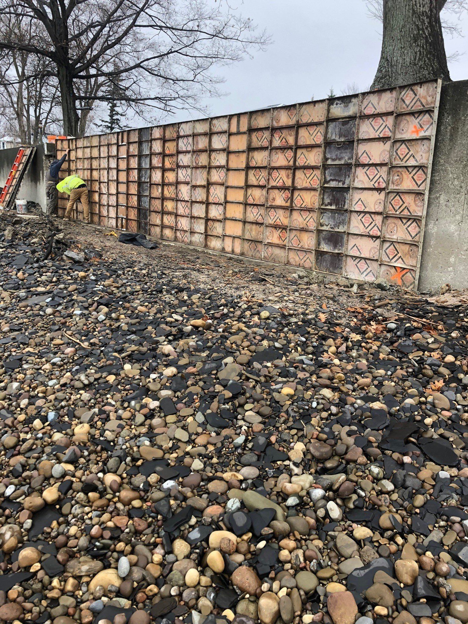 A pile of rocks is sitting in front of a concrete wall being built.