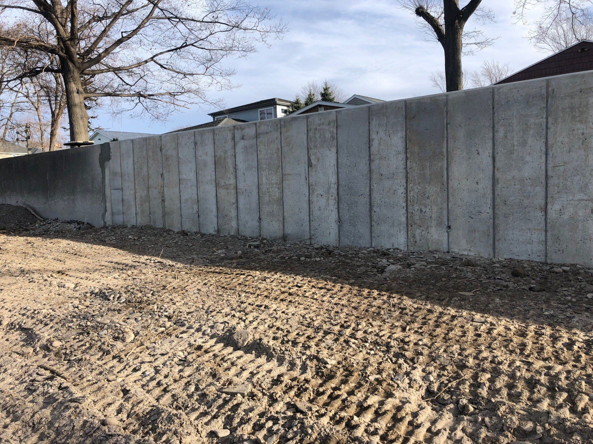 A large concrete wall is sitting on top of a dirt hill.