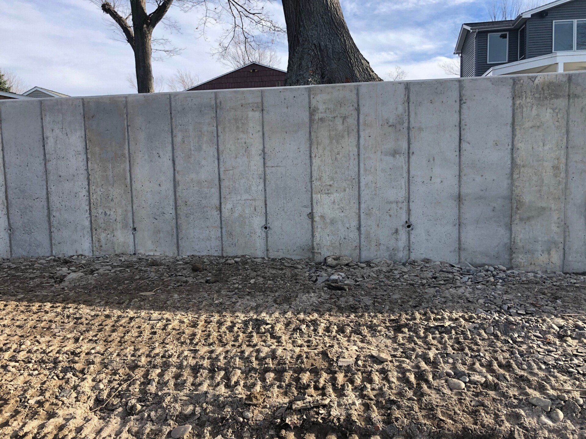 A concrete wall with a tree in the background and a house in the background.