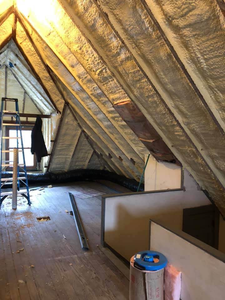 A ladder is hanging from the ceiling of an attic.