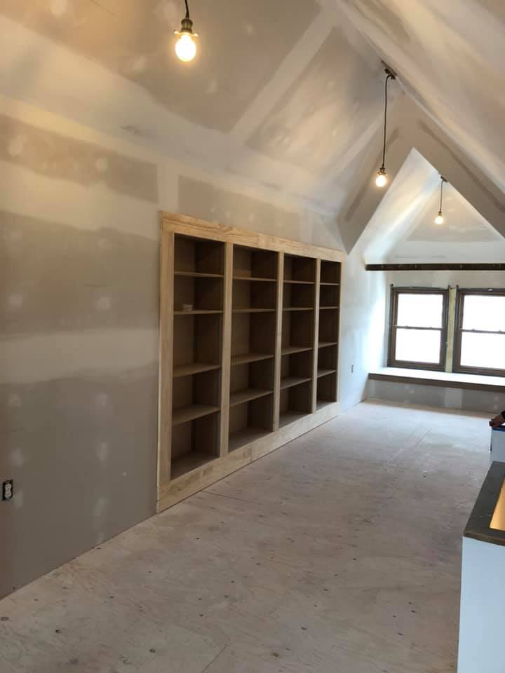 An empty room with a vaulted ceiling and shelves.