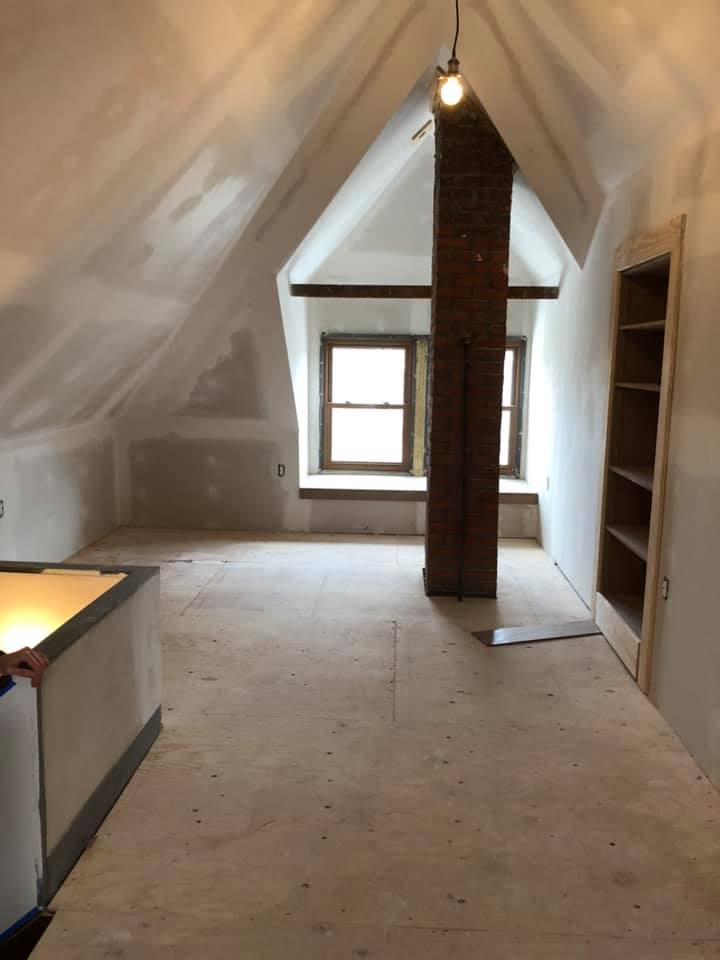 An empty room with a brick chimney in the middle