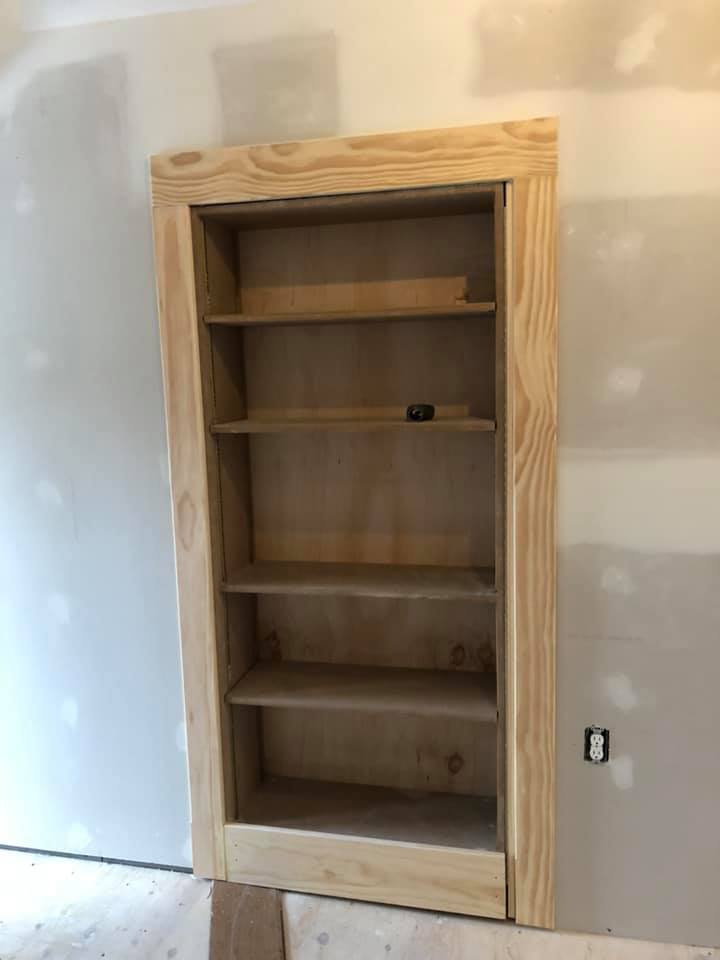 A wooden bookshelf is sitting in a room next to a wall.