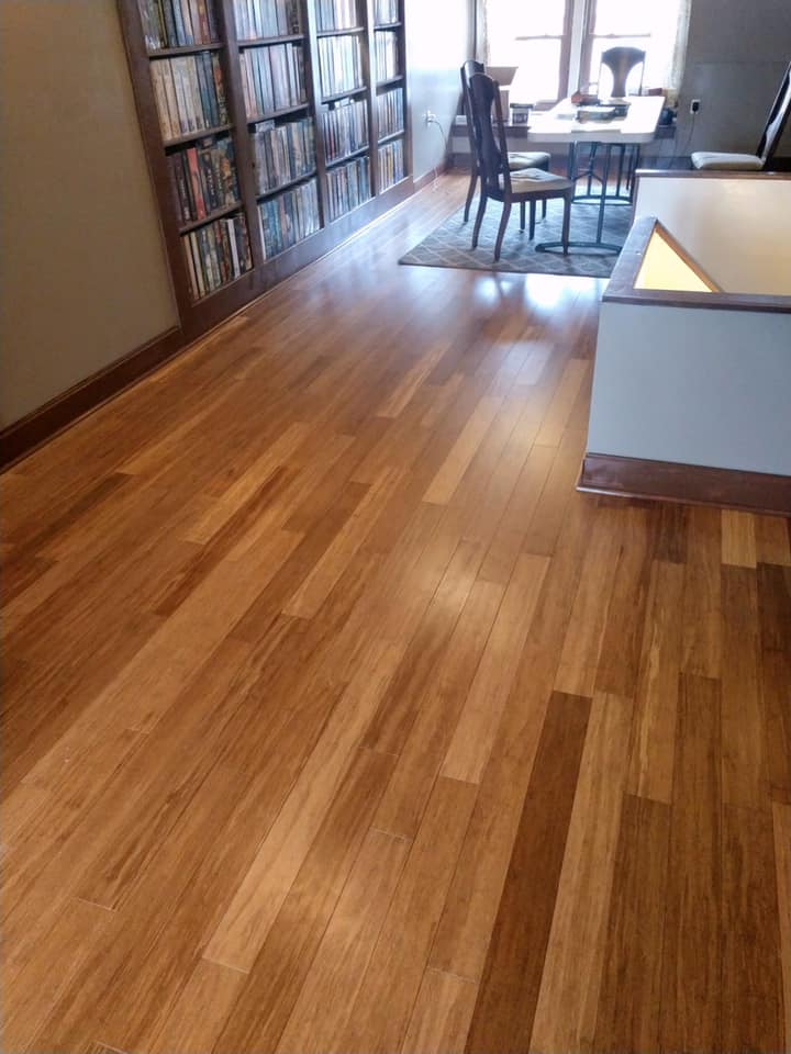 A wooden floor in a living room with a table and chairs.