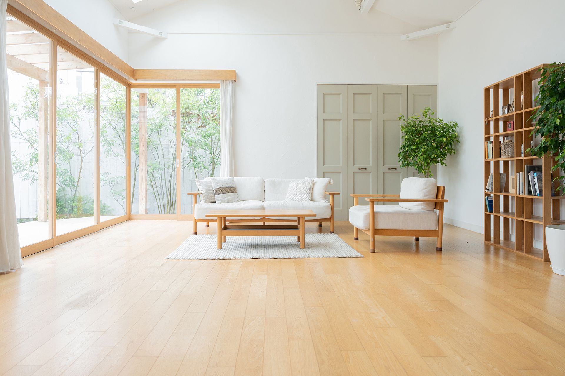 A living room with a couch , chair , coffee table and lots of windows.