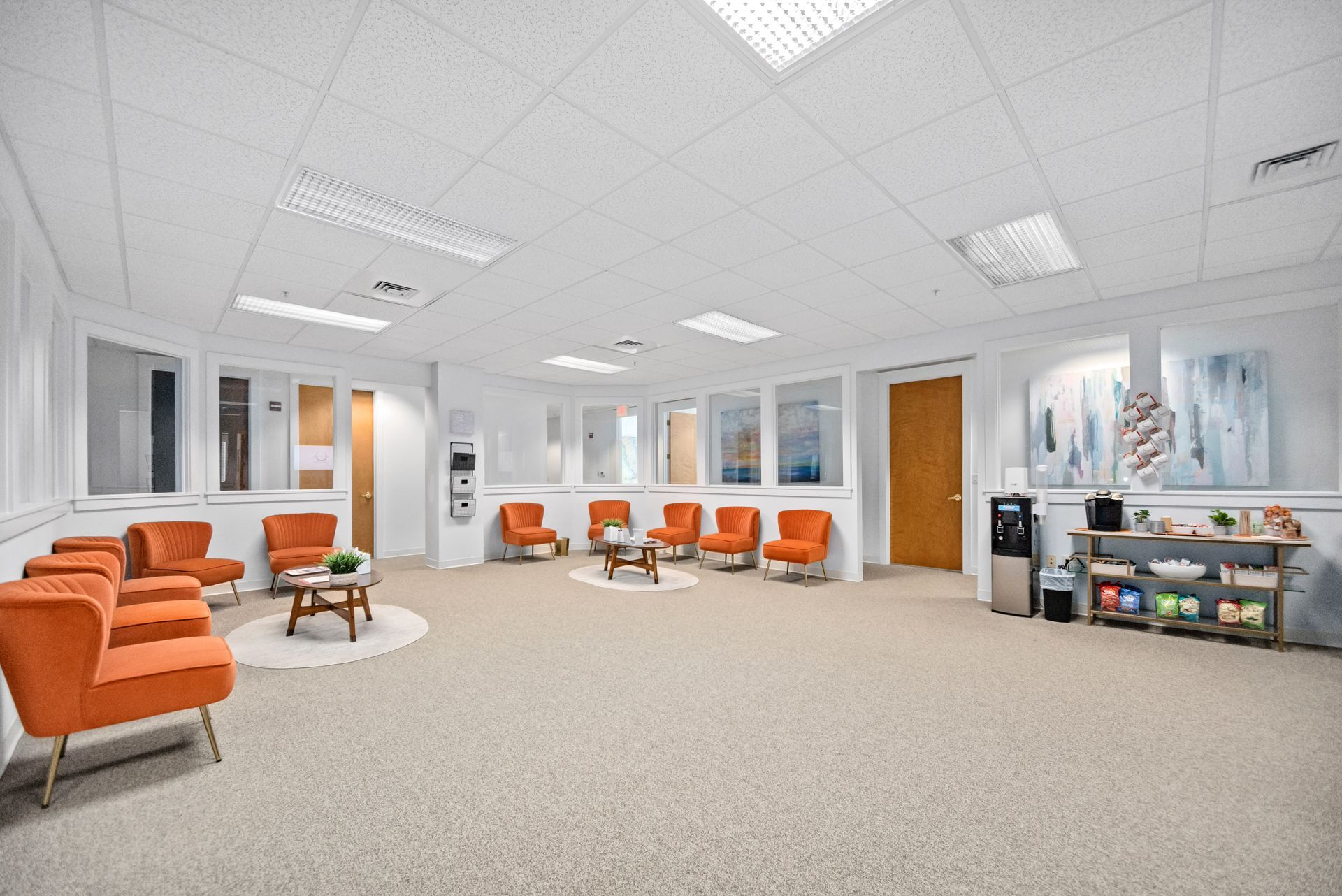 A large waiting room with orange chairs and a coffee table.