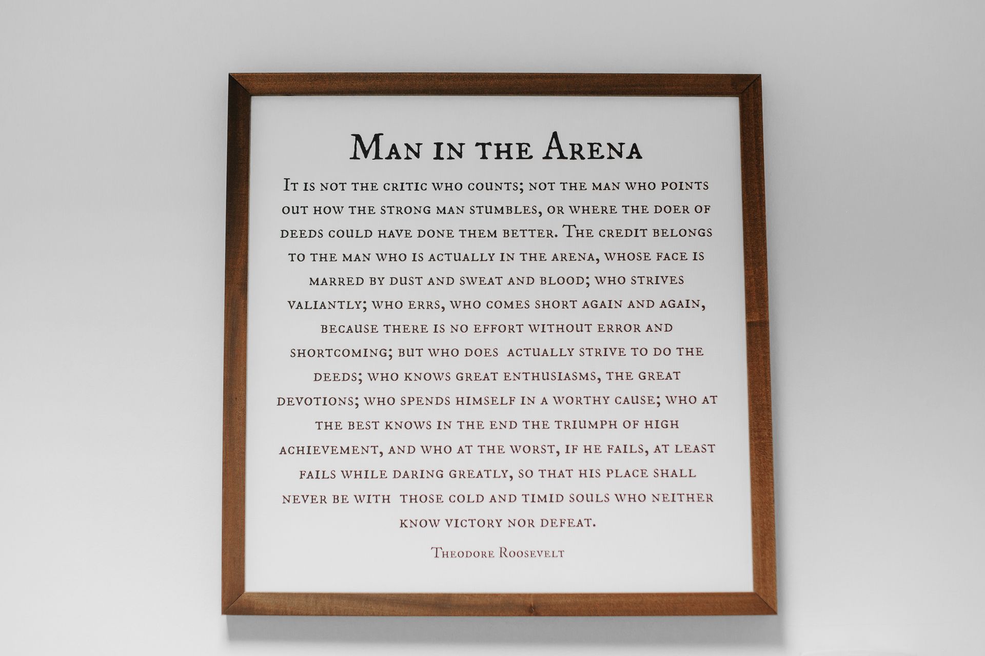 A framed sign that says ' man in the arena ' on it