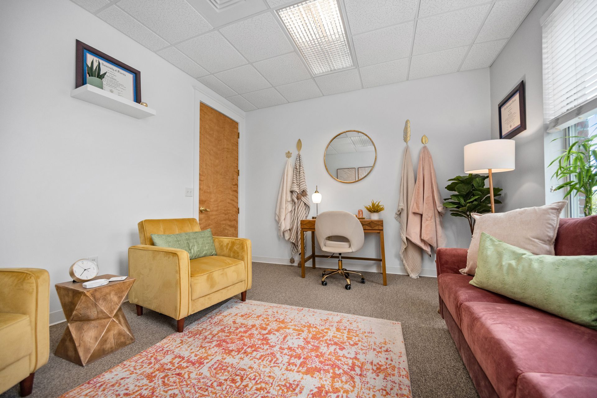 A living room with a couch , chair , desk and mirror.