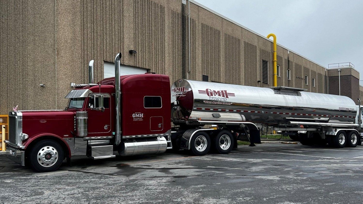 A red semi truck is parked in front of a building.