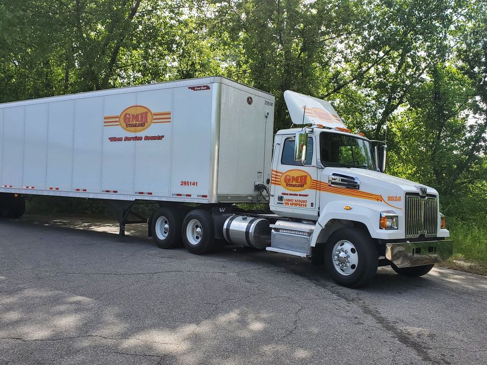 A white semi truck is parked on the side of the road.