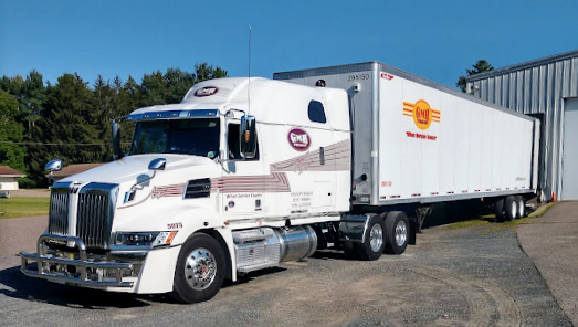 A semi truck is parked in front of a building with a rainbow in the sky