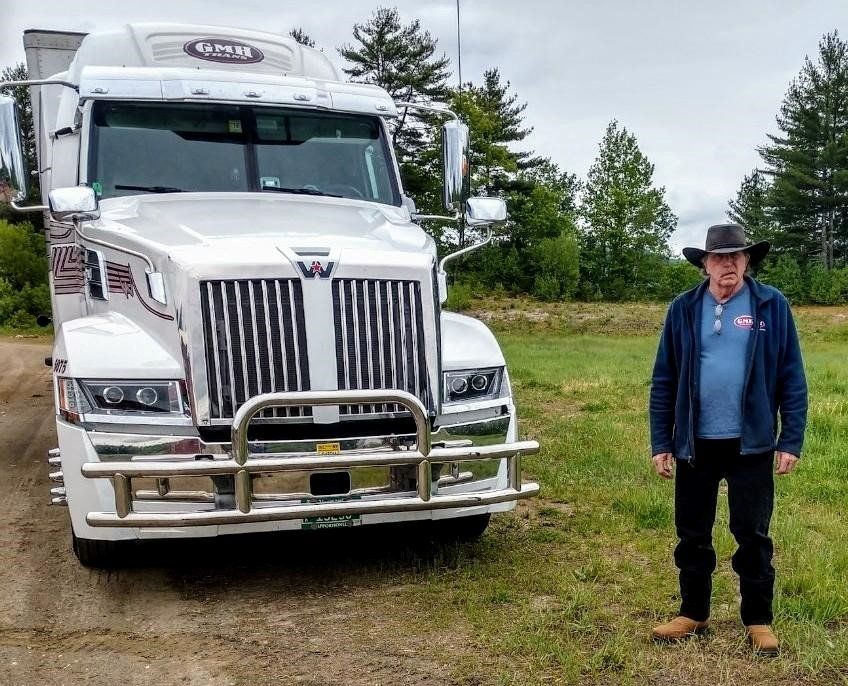 A black semi truck is parked next to a blue semi truck.