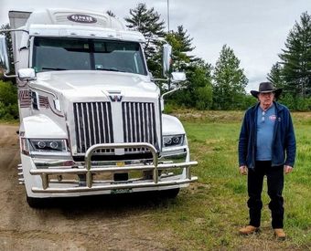 A black semi truck is parked next to a blue semi truck.