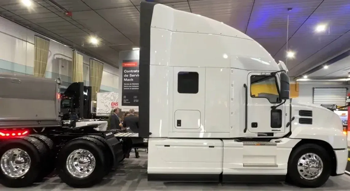 A white semi truck is parked in a warehouse.