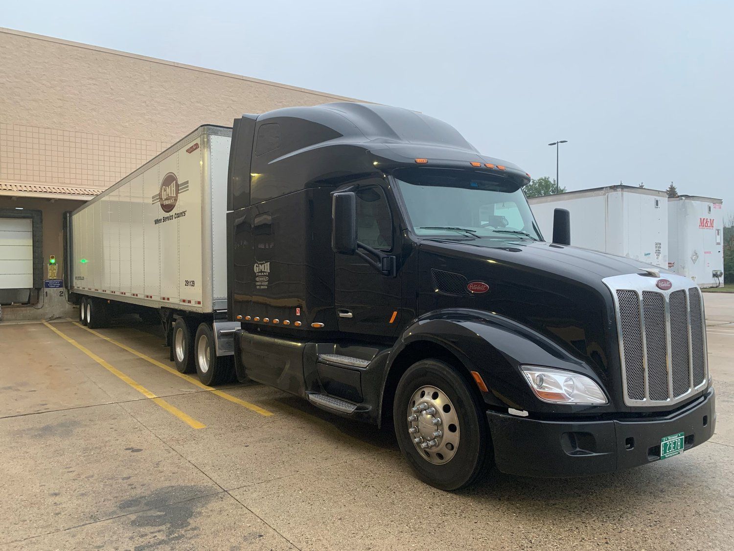 A black semi truck is parked in a parking lot next to a building.