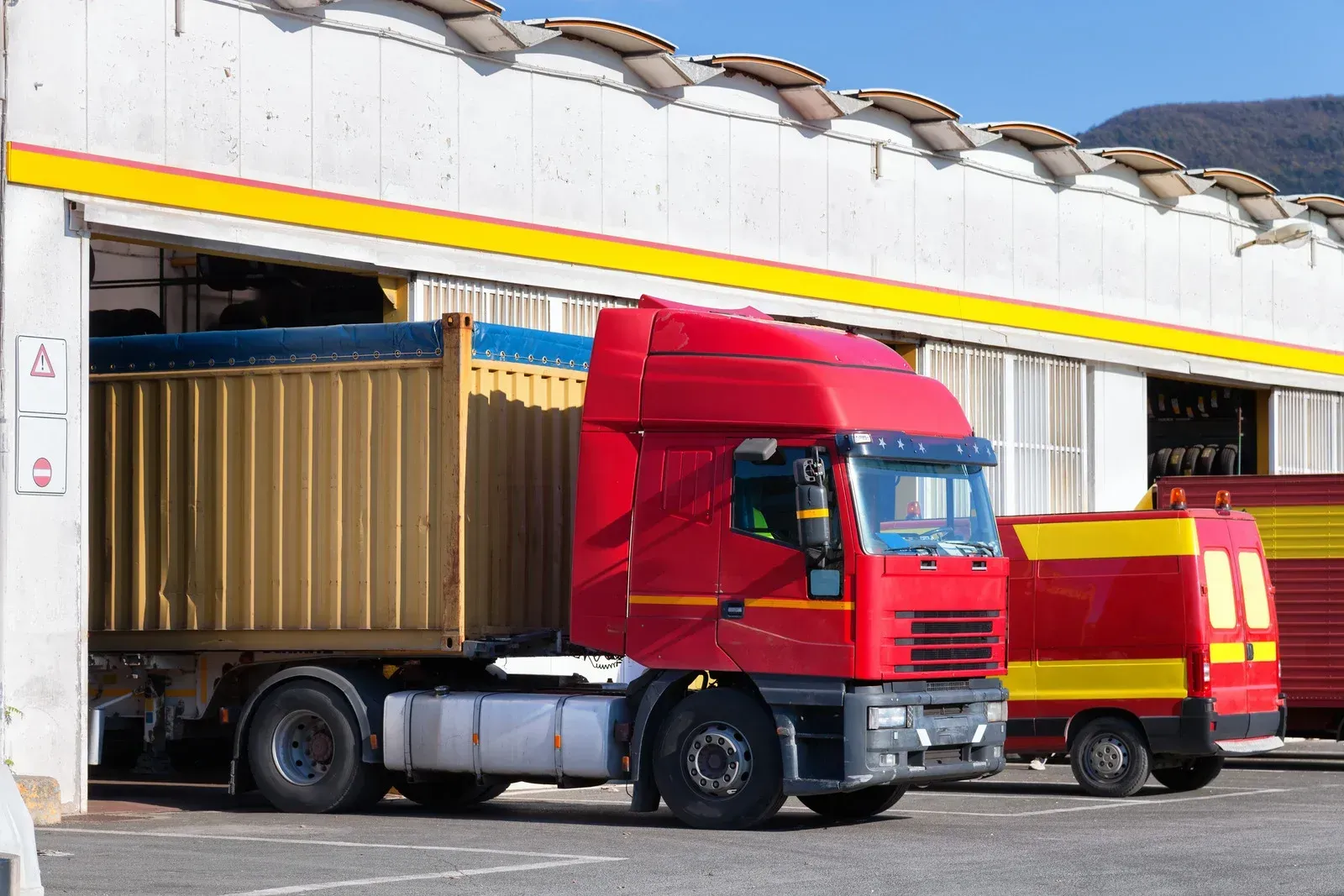 A red semi truck is parked in front of a building