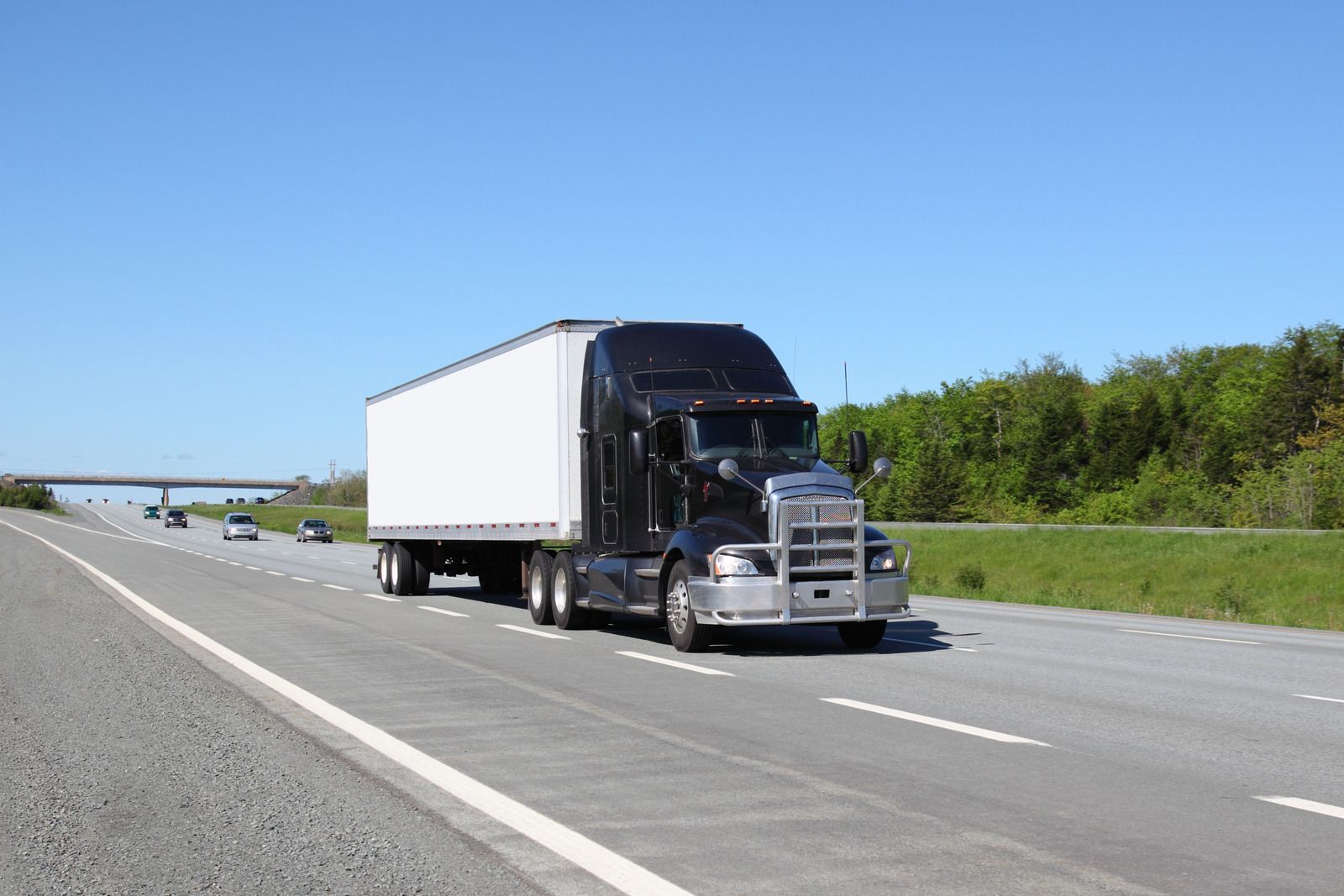 A semi truck with a white trailer is driving down a highway.