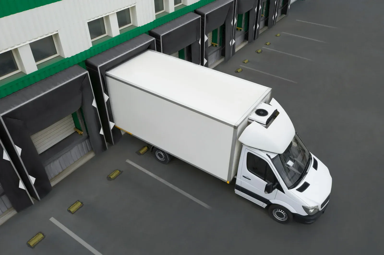 A white truck is parked in front of a warehouse.
