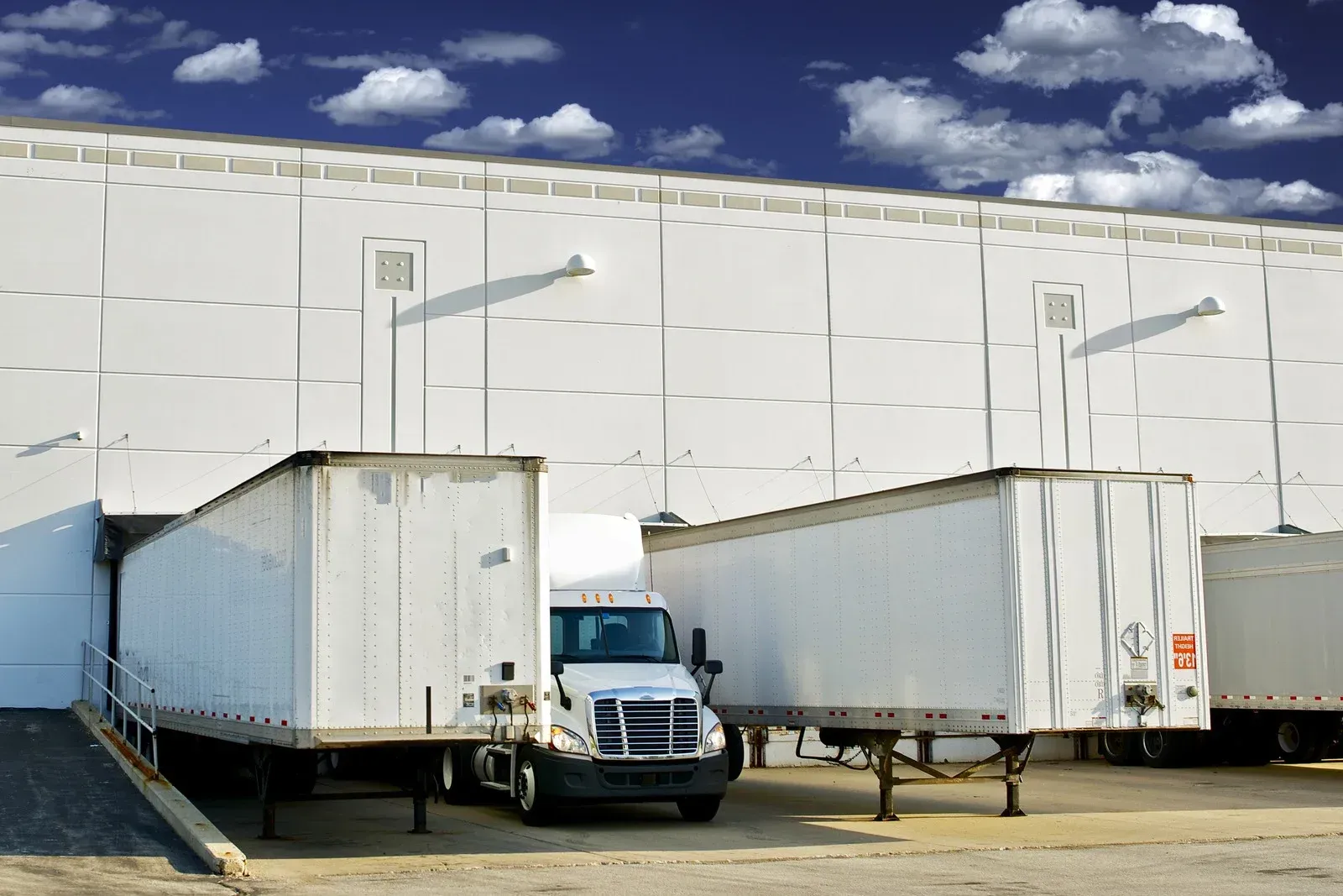 A truck and trailers are parked in front of a building.