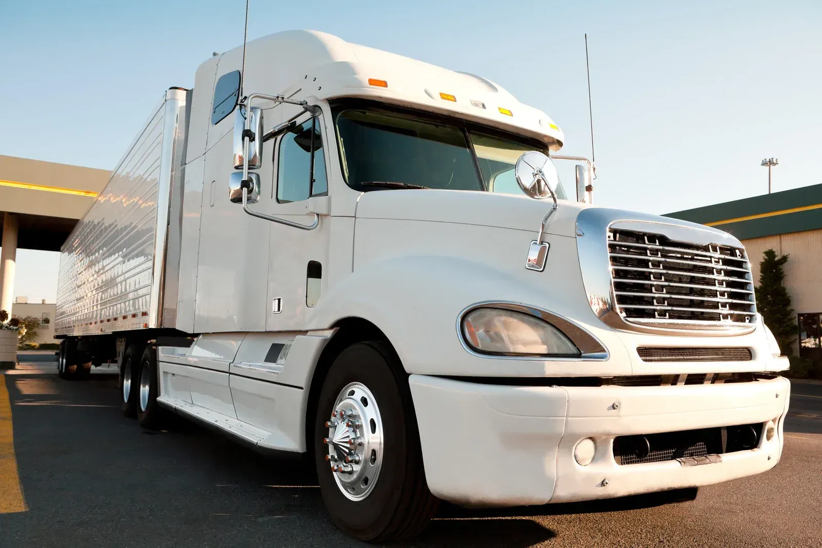 A white semi truck is parked in front of a building.