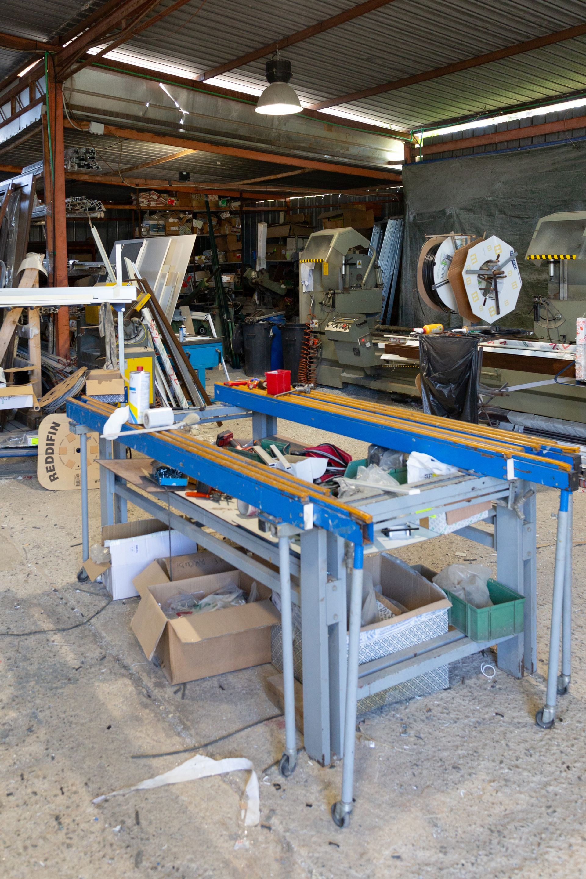 Un magazzino pieno di macchinari e tavoli per produrre gli infiss