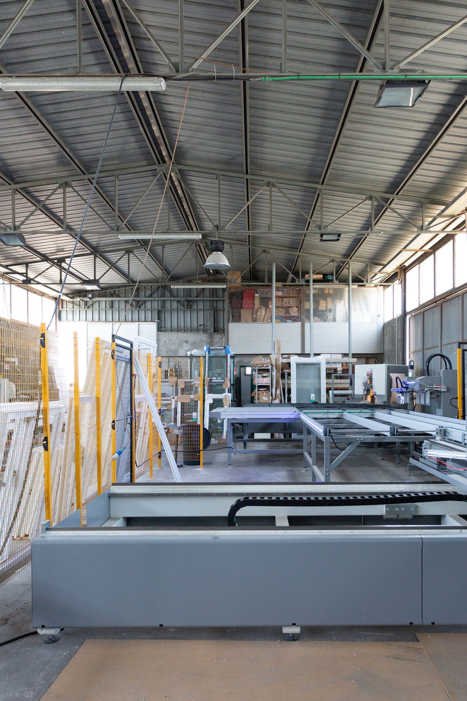 Un grande magazzino pieno di macchinari per la produzione di finestre