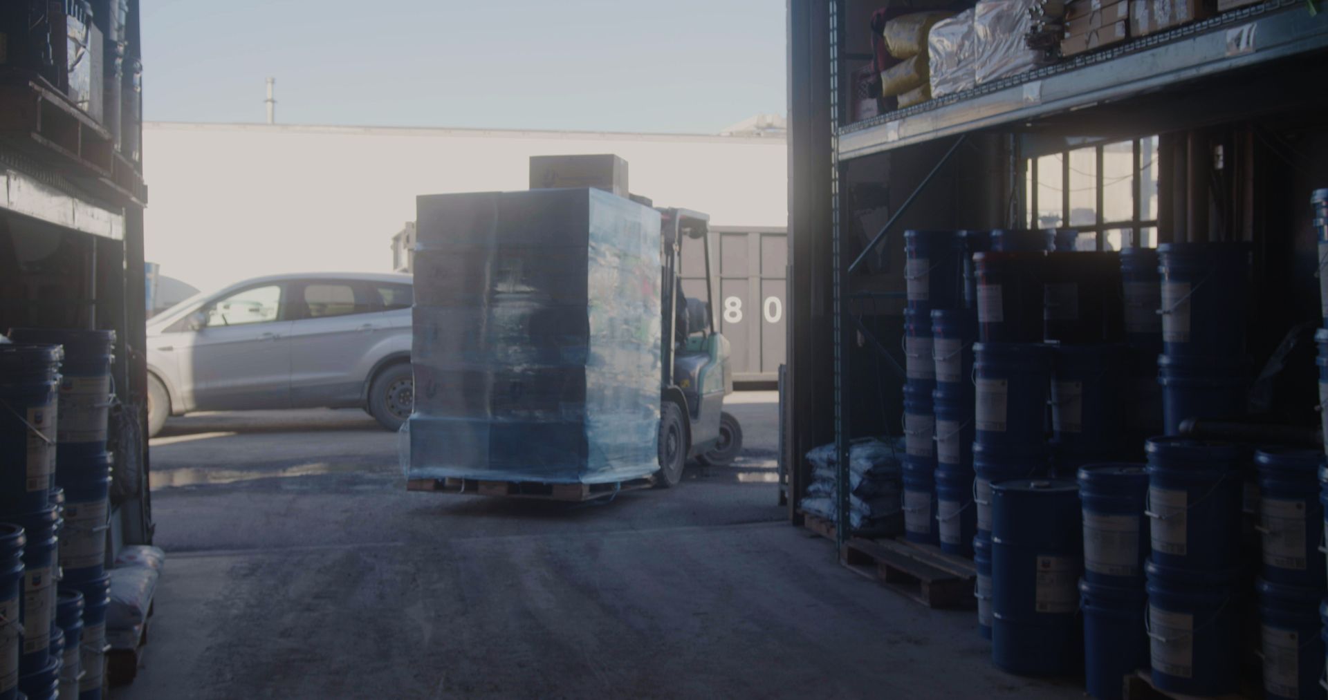 A forklift is carrying a large container in a warehouse.