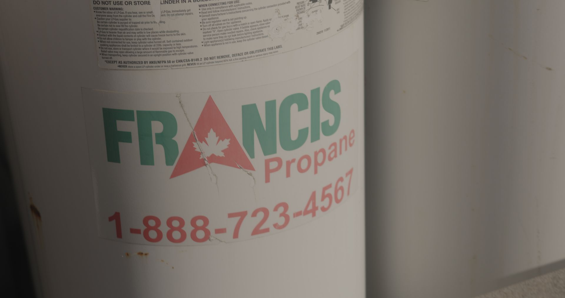 A close up of a propane tank on a wall.
