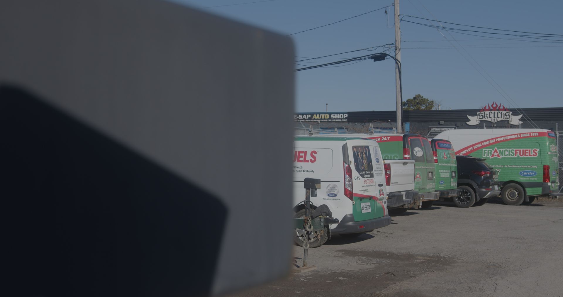 A row of green and white vans are parked in a parking lot.