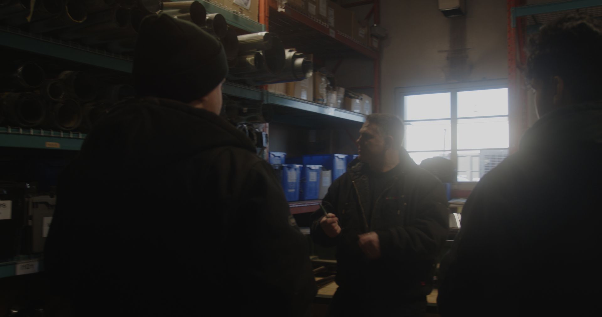 A group of people are standing in a dark room in front of a window.