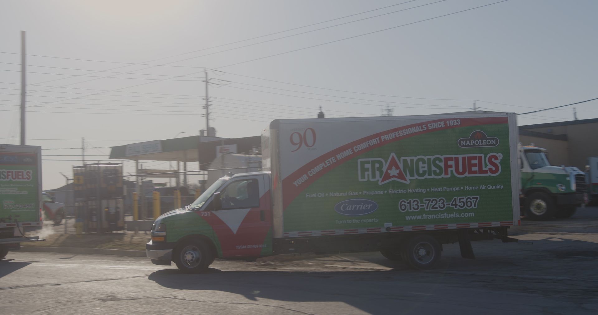 A green and white truck is parked on the side of the road.